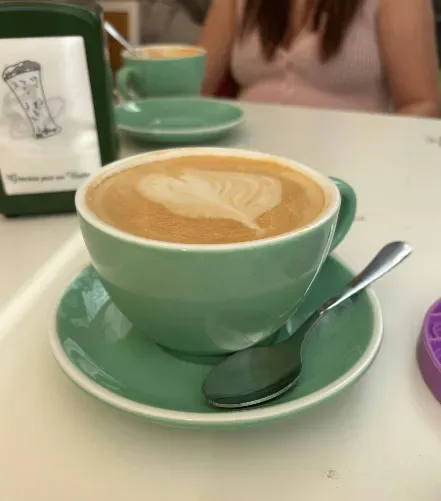 Café con leche con arte latte en taza verde pastel
